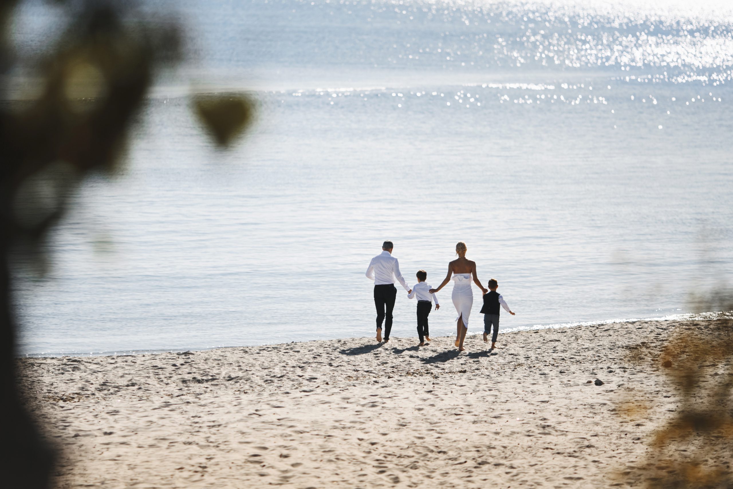Back view of running family on the beach on the sunny day near t